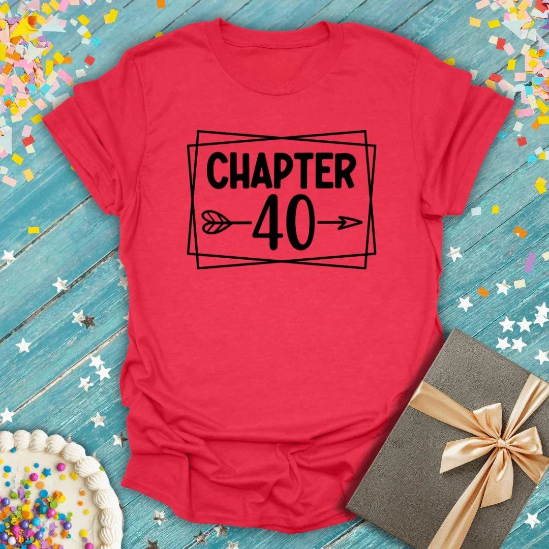 Red 'Chapter 40' birthday tee with confetti, cake, and gift on blue wood background
