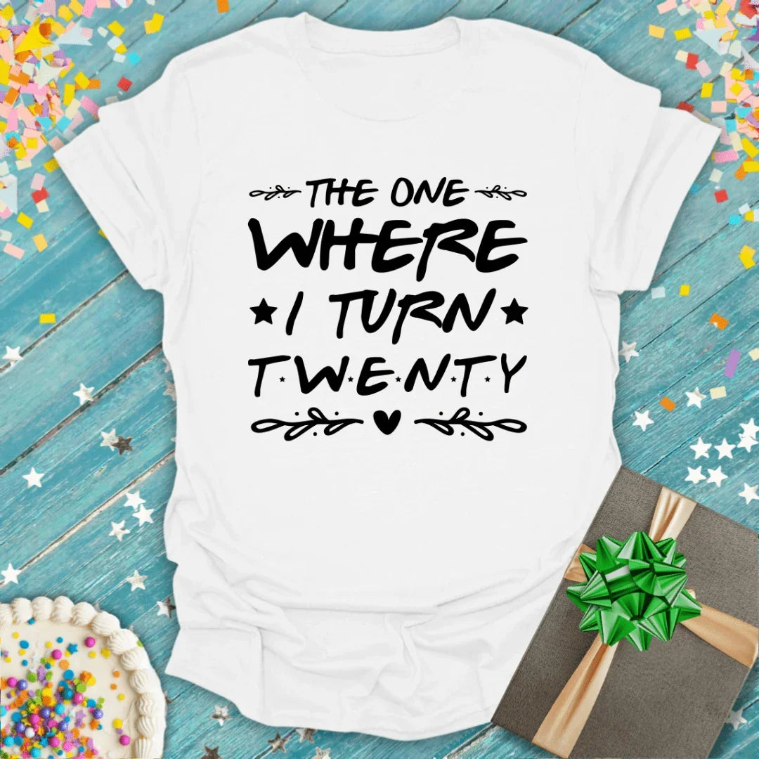 White birthday tee saying 'The One Where I Turn Twenty' with confetti, cake, and gift — perfect for 20th birthday celebrations.