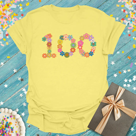 Yellow 100th birthday shirt with floral design, surrounded by confetti, cake, and gift box