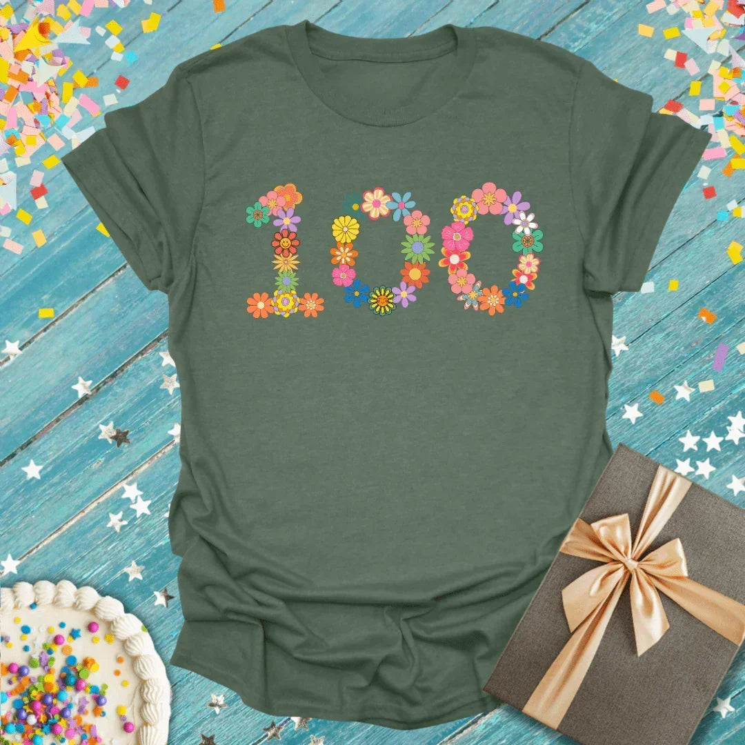 Green t-shirt with floral '100' design, perfect for birthdays or celebrations, paired with cake and gift.