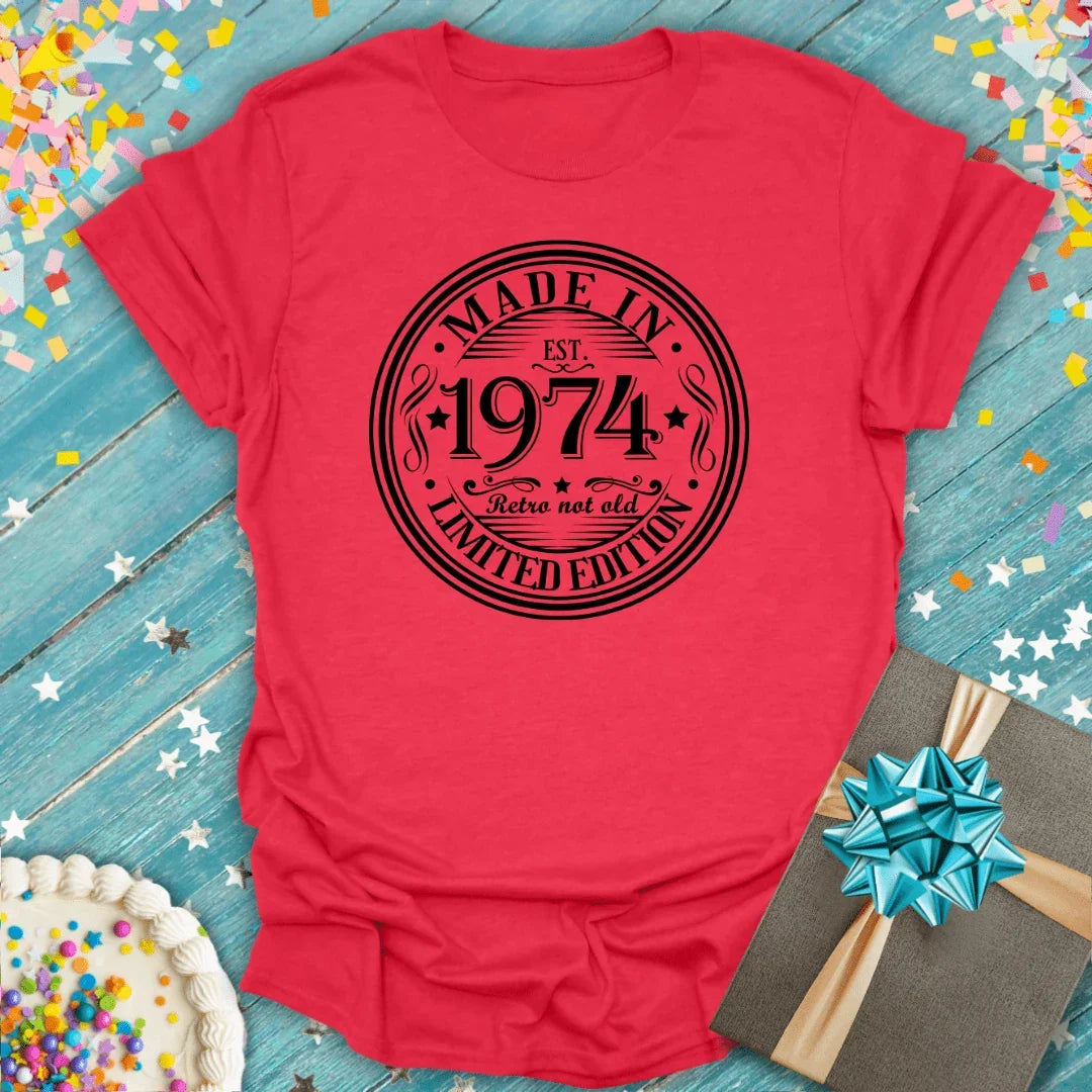 Red 'Made in 1974' birthday tee with retro design, gift box, and cake on confetti background