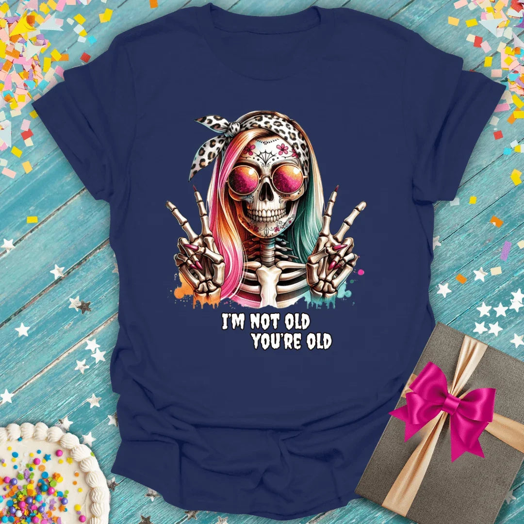 Fun skeleton tee with 'I'm Not Old You're Old' quote, perfect for birthdays or trips. Soft graphic tee with confetti & gift.