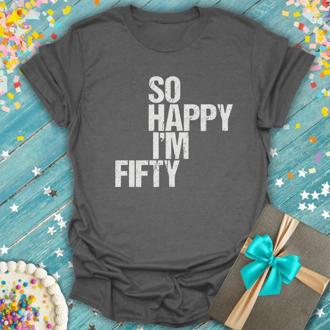 Gray 'So Happy I'm Fifty' birthday tee with cake, gift, and confetti on blue wood