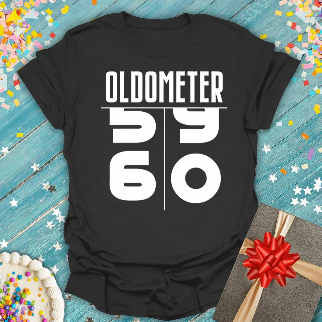 Black 'Oldometer 59 to 60' birthday tee with cake, gift, and confetti on blue wood
