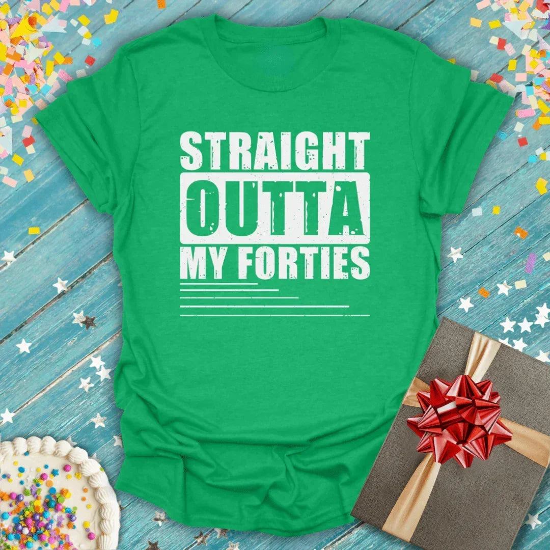 Green 'Straight Outta My Forties' birthday tee with cake, gift, and confetti on blue wood