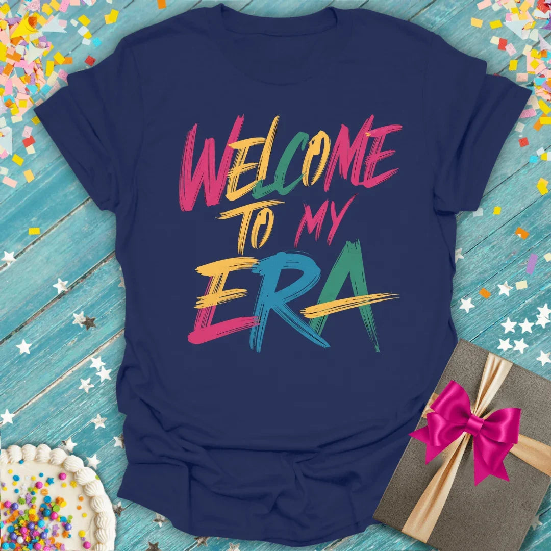 Navy 'Welcome to My Era' birthday tee with confetti, cake & gift—perfect for milestones & celebrations.