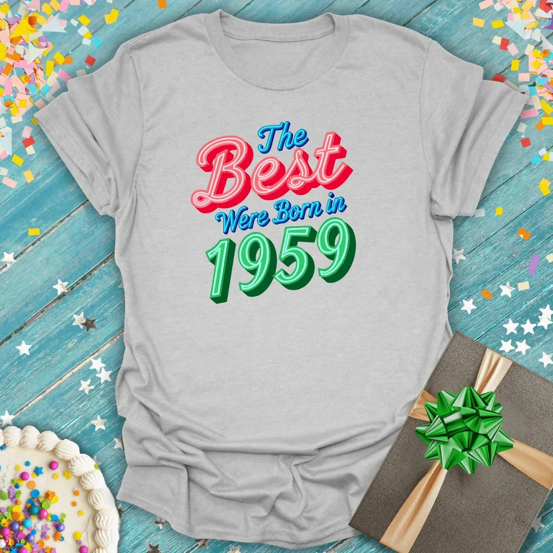 Gray birthday tee saying 'The Best Were Born in 1959' with cake, gift, and confetti on blue wood