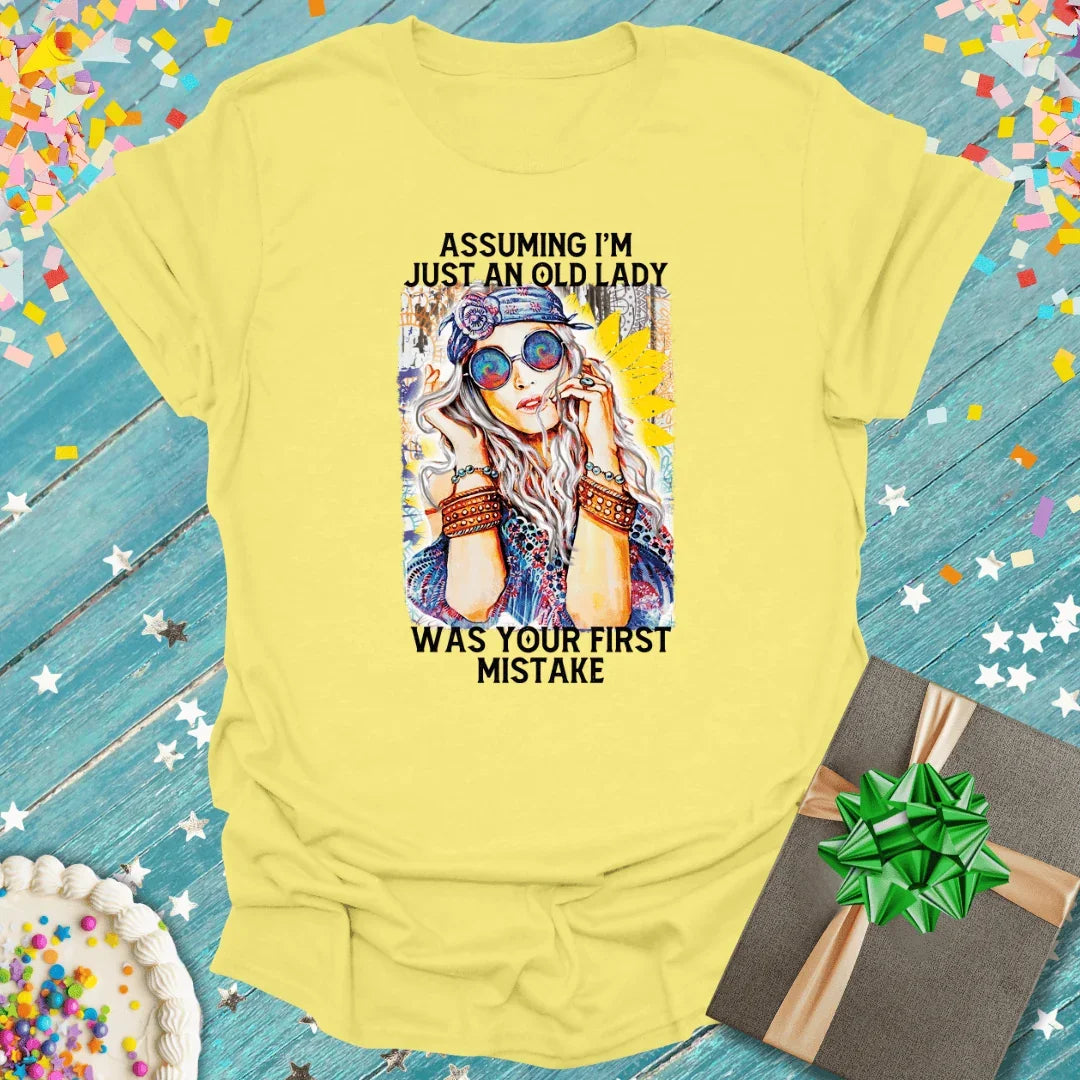 Yellow tee with bold graphic: 'Assuming I'm just an old lady was your first mistake' — perfect for birthdays, gifts, or fun trips.
