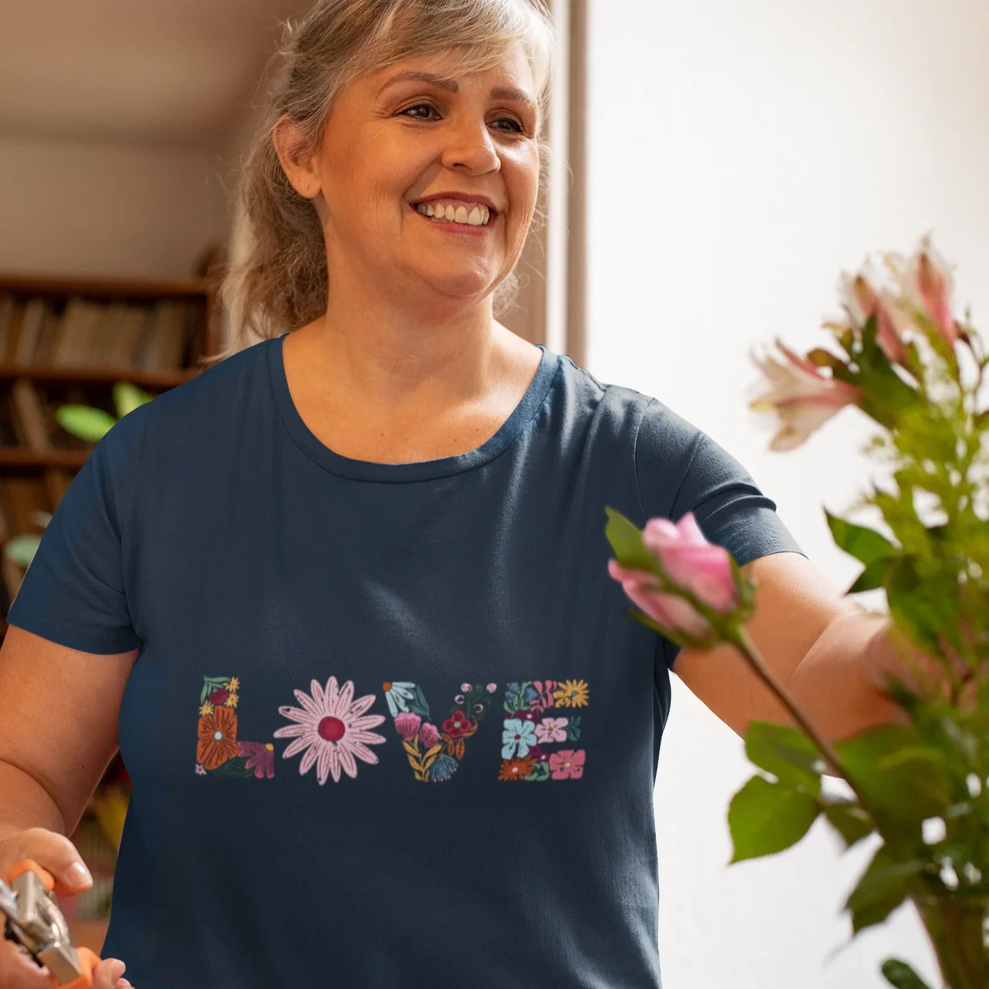 Navy t-shirt with 'LOVE' in colorful floral letters, worn by smiling woman. Epic Era Tees design.