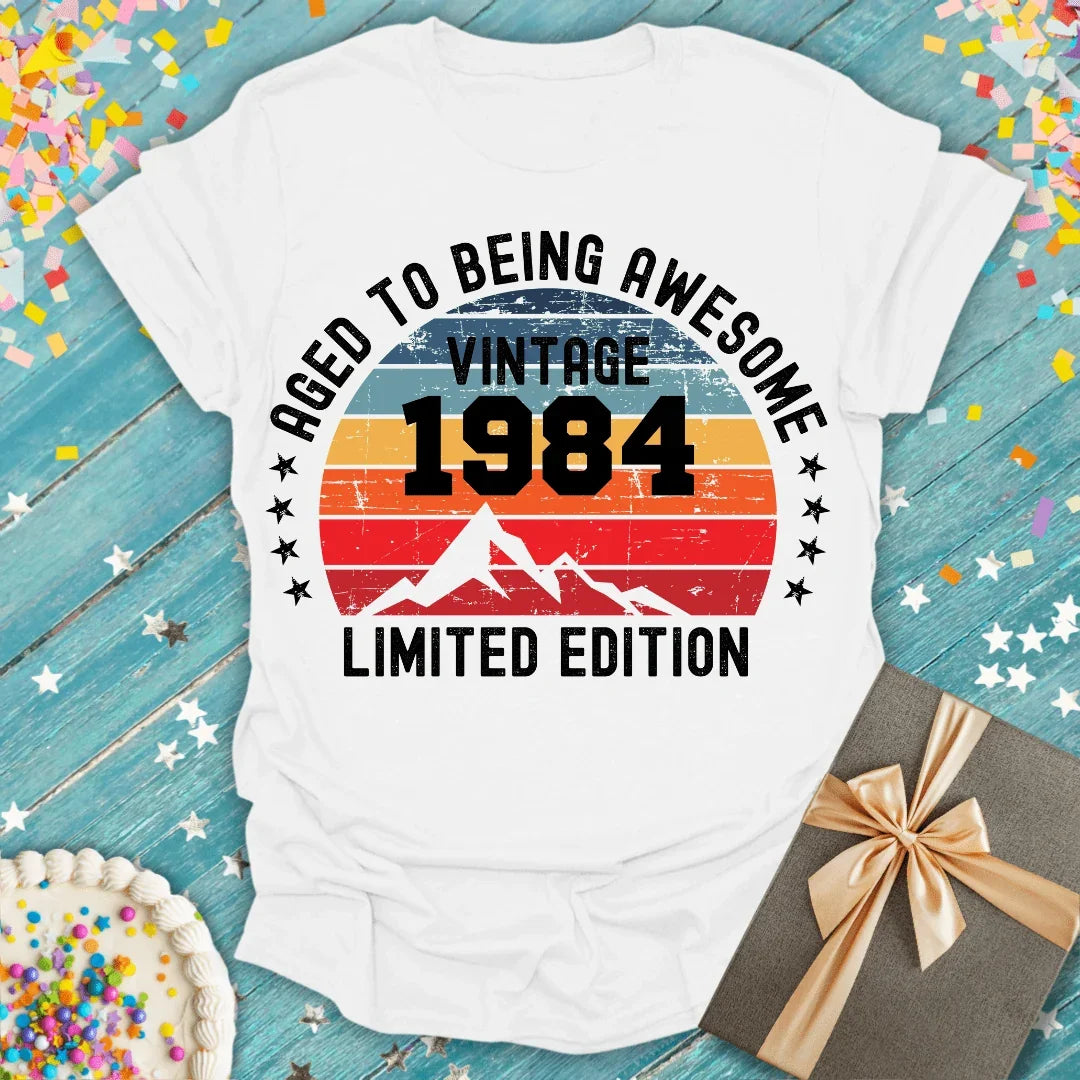 Vintage 1984 birthday tee, 'Aged to Being Awesome' limited edition, with cake and gift on confetti backdrop