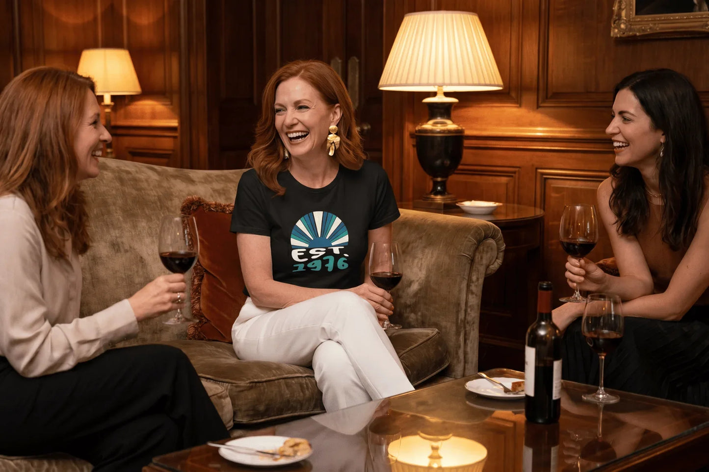 Black t-shirt with retro sunburst graphic and 'EST. 1976' text, worn by woman laughing with friends. Epic Era Tees.