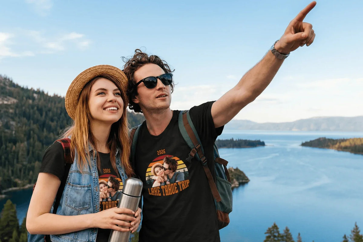 Couple in matching Lake Tahoe trip 2026 tees pointing at scenic lake view, perfect for travel memories and birthday gifts.