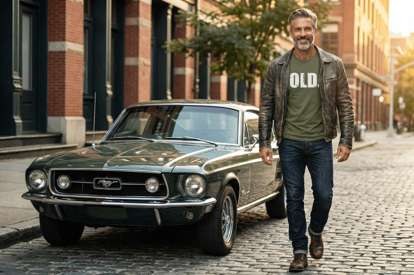 Man in 'OLD' tee walking beside classic green Mustang on cobblestone street