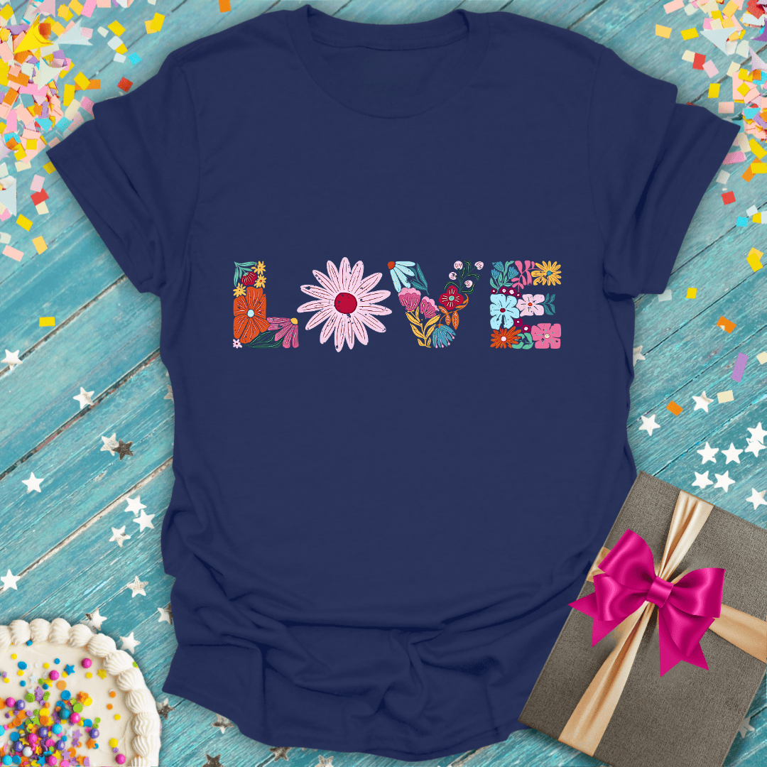 Navy t-shirt with floral 'LOVE' design, gift box, and birthday cake on confetti background