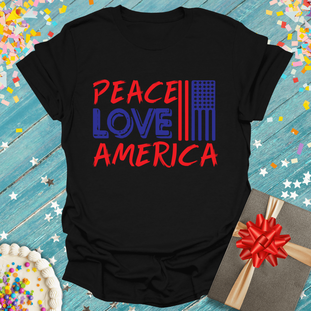 Black Peace Love America t-shirt with flag design, gift box, and birthday cake on blue wood