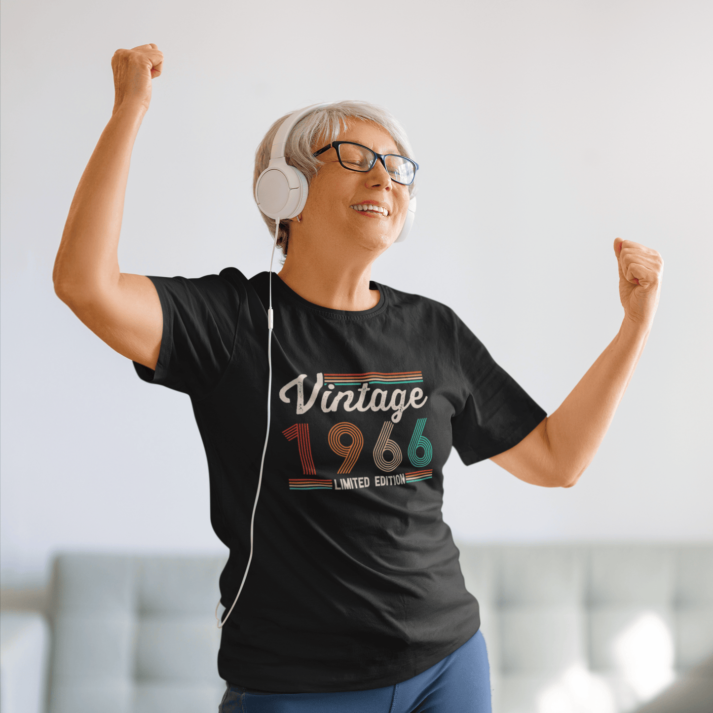 Woman dancing in black Vintage 1966 limited edition tee, celebrating birthday or milestone with headphones on