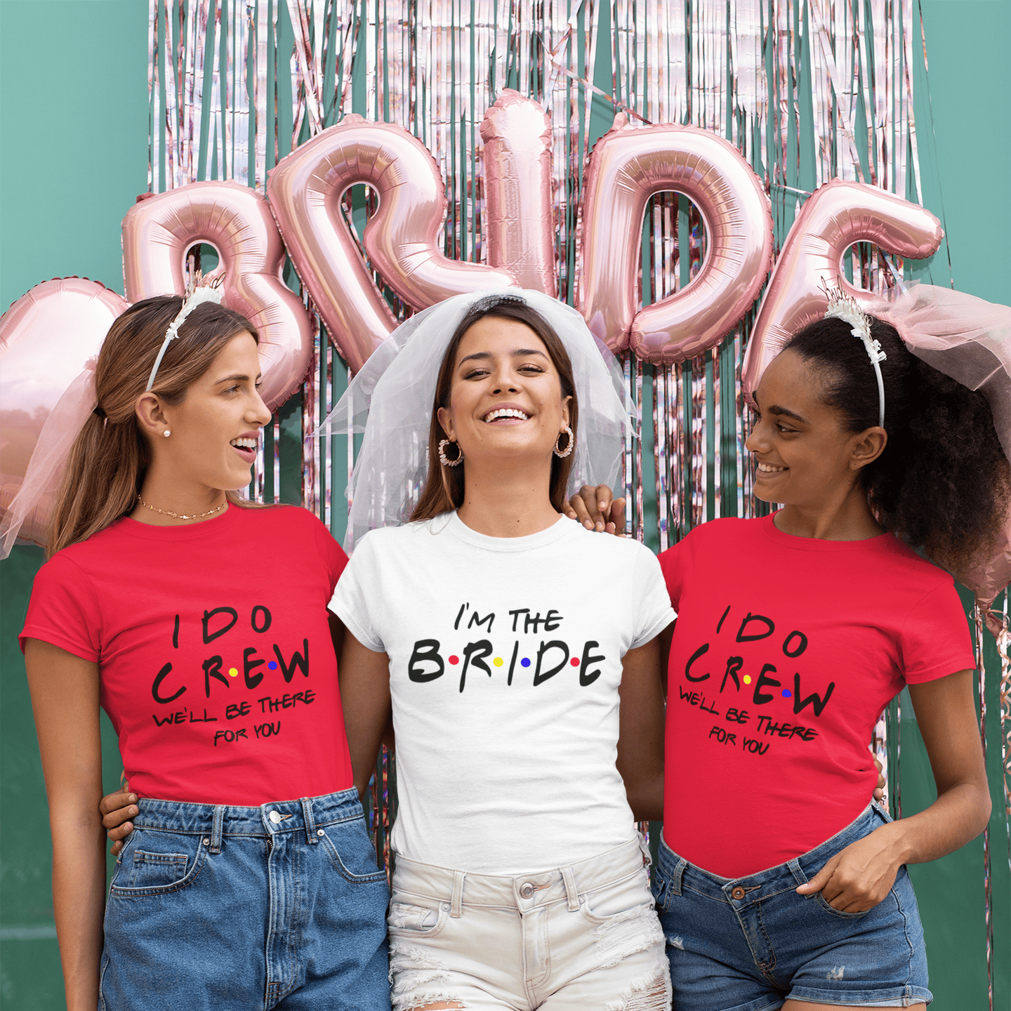 Bride and bridesmaids in fun wedding tees, 'I'm the Bride' and 'I Do Crew,' celebrating with pink balloons and veils.
