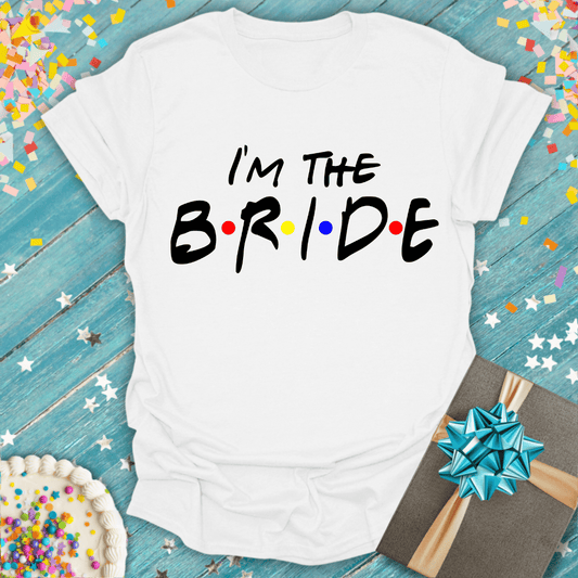 I'm the Bride t-shirt with colorful dots, on blue wood with confetti, cake, and gift—perfect for bridal parties