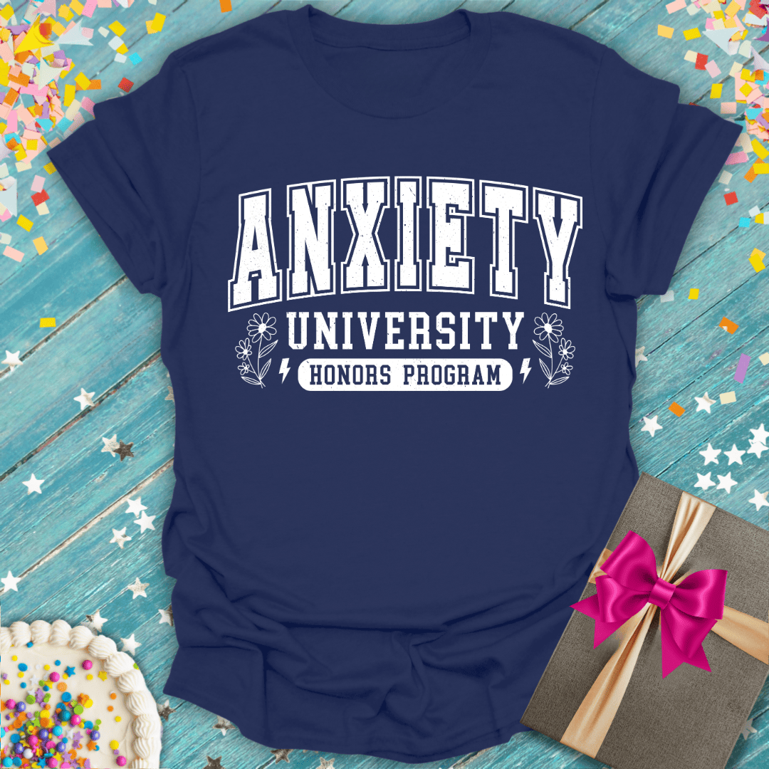 Navy blue t-shirt with 'Anxiety University Honors Program' text on a wooden surface with colorful confetti.