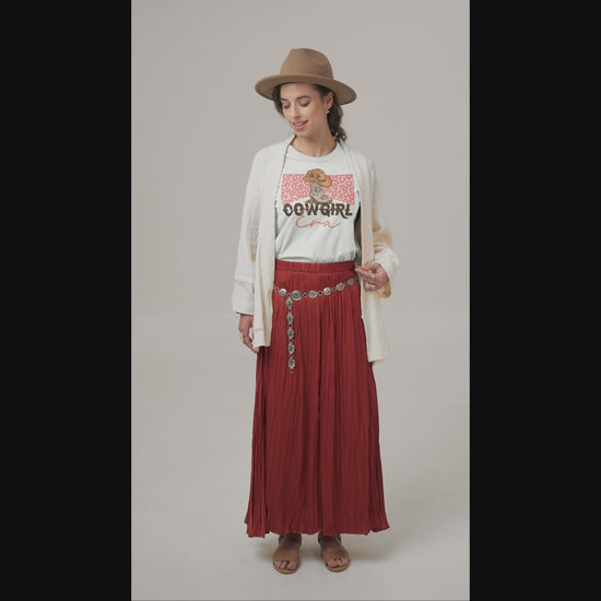 Woman in hat, long skirt with a Cowgirl Era t-shirt on